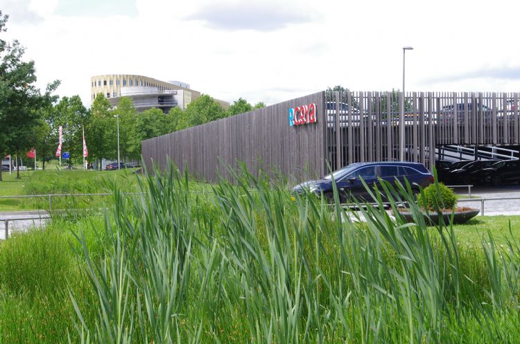 Een lamellenwand houdt geparkeerde auto's uit het zicht. Een lamellenwand houdt geparkeerde auto's uit het zicht.