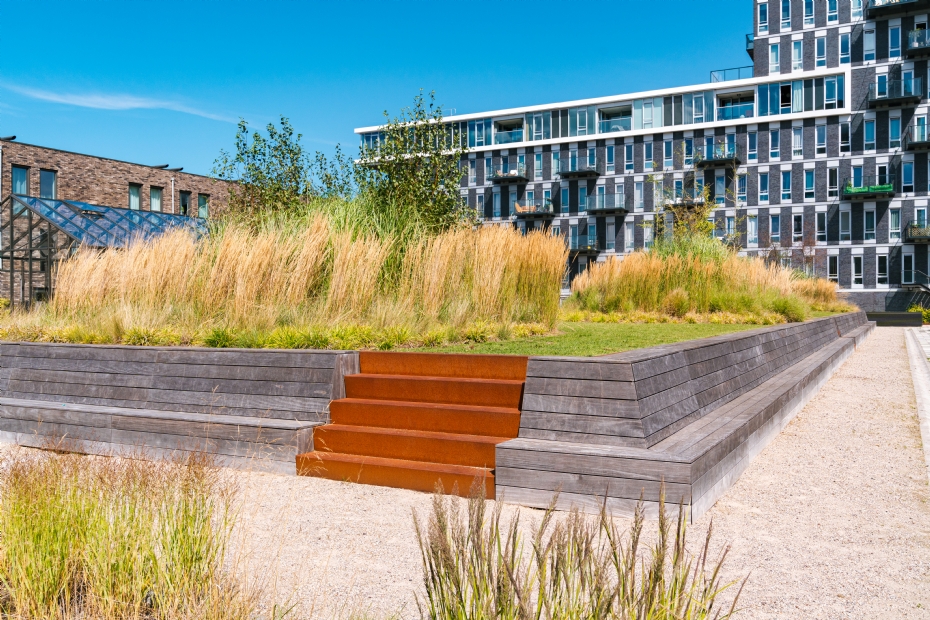 Door de lange zitbank en het groen vormt de verhoging een mooi geheel met de plantenbakken in de gezamenlijke daktuin